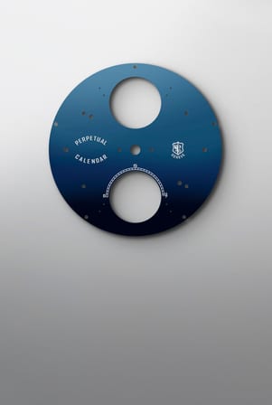 This image shows a dark blue watch dial, featuring "PERPETUAL CALENDAR" text, a logo with "GENEVE", and various cut-outs for its calendar functions.