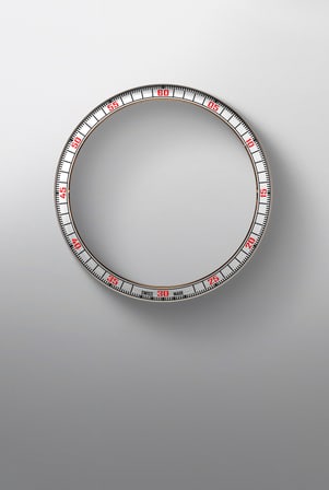 This image shows a circular, metallic watch flange with a minute track and red Arabic numerals (05-60) at five-minute intervals.