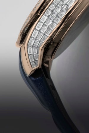 The image is a close-up of the Roger Dubuis Excalibur Double-tourbillon Watch RDDBEX1183, highlighting its rose gold case and the invisible baguette-cut diamond setting on the bezel. A blue strap is also visible.